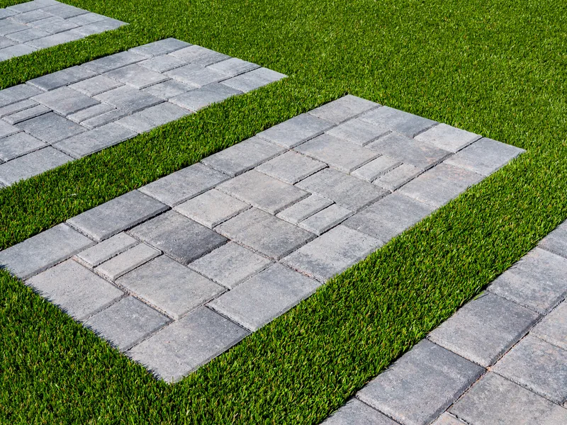 Grey paver stepping stones set into finished artificial turf. The turf is cut tight around every stone.